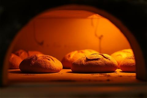 Glowing interior of a large bakery oven with loaves baking inside.